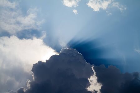 Sun ras bursting through clouds in a blue sky 