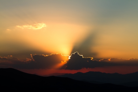 golden sunset in clouds over high mountainsの写真素材