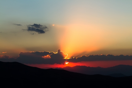golden sunset in clouds over high mountainsの写真素材