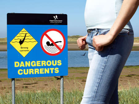 female beside the notice about dangerous currentsの写真素材