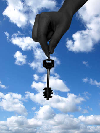 key at hand on the cloudy backgroundの写真素材