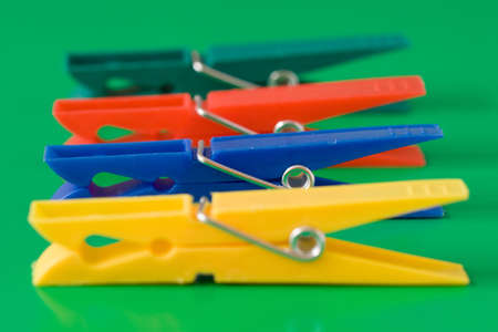 four colorful clothespins isolated on green backgroundの写真素材
