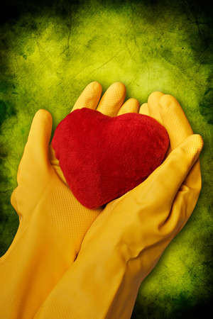 hands in yellow gloves hold red heartの写真素材