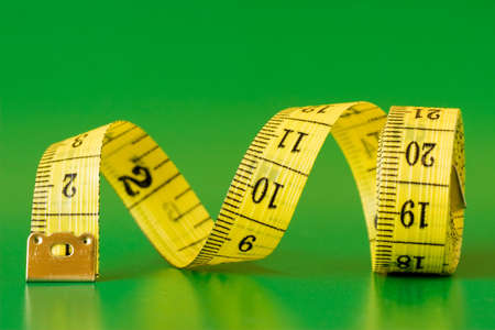 close-up of a yellow measure tape,isolated on green background