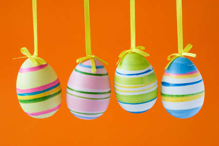 four colorful easter eggs isolated on orange backgroundの写真素材