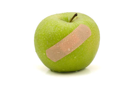 green injured apple with plaster,isolated on white backgroundの写真素材