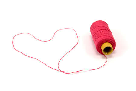 Heart shape made of red thread with spoolの写真素材