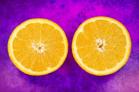 two halves fresh orange fruit on grunge purple backgroundの写真素材