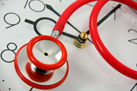 close-up of red stethoscope on silver clockの写真素材