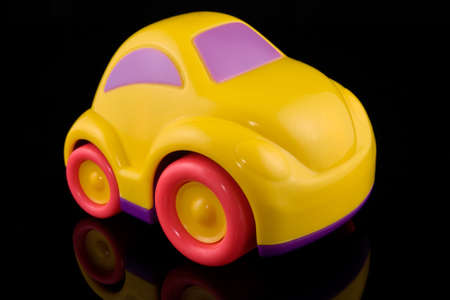 yellow plastic car with reflection on black background