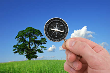 human hand with compass on nature background.