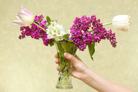 Female hand holding vase with various flowers. の写真素材