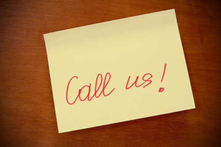 wooden board  with yellow  sticky note "call us" .の写真素材