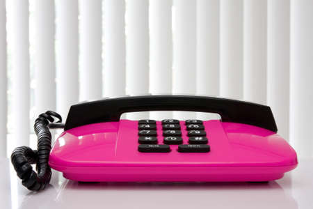 pink office telephone with reflection on the table.の写真素材