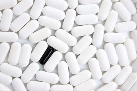 many white pills with one black pill in a middle.