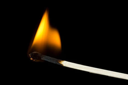Burning flame on a  matchstick over a black background 