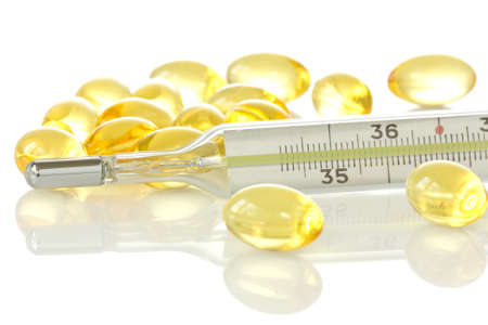 medical thermometer and yellow pills on white background