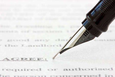 black ink pen over a printed agreement