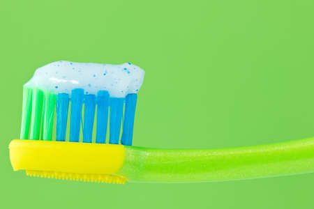 	toothbrush with toothpaste isolated on green background