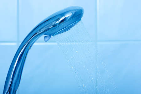 Shower head with water stream on blue background の写真素材