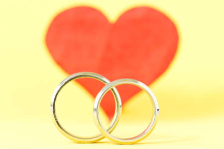 silver rings and red red  heart on yellow backgroundの写真素材