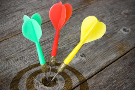 Colorful darts hitting  target on a wooden planks