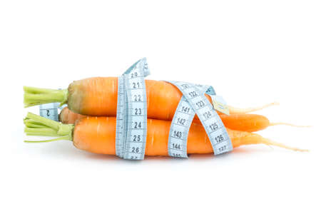 Carrot wrapped by measure tape on the white backgroundの写真素材