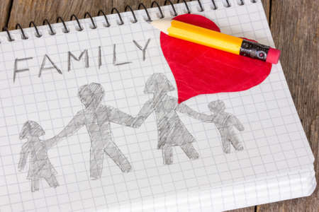 Pencil and heart on the notebook with  drawing of familyの写真素材