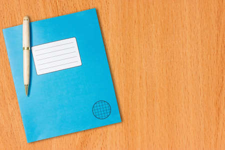 Blue exercise book with a pen on the wooden tableの写真素材