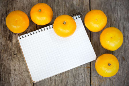 Clementines and  notebook on a wooden background の写真素材
