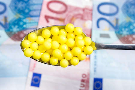 Medical treatment and cost concept: spoon with pills on money  background の写真素材