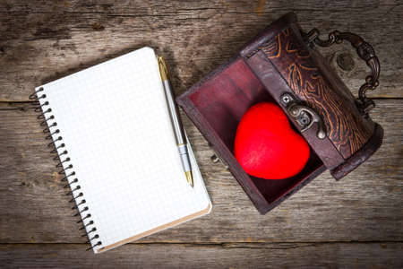  Red heart in the  box and notebook with pen on wooden floorの写真素材