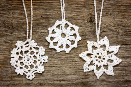 Crochet christmas snowflakes hanging on wooden wallの写真素材