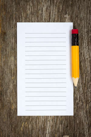 Pencil and lined paper on the wood backgroundの写真素材