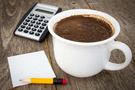 Coffee cup, calculator  and empty paper sheet with pencil on wooden backgroundの写真素材