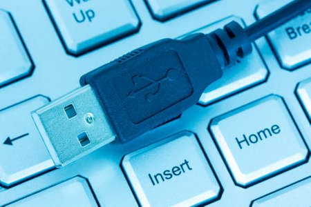 Computer keyboard and usb devise tinted in blue tone  の写真素材