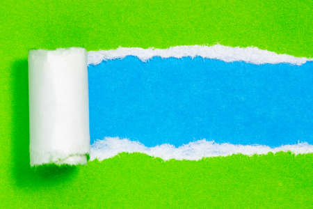 Torn green color paper on blue color background with space for text の写真素材