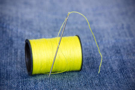 Needle with yellow thread on jeans materialの写真素材