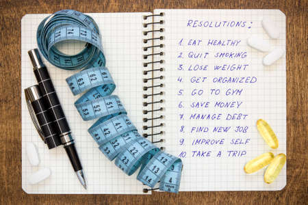 Resolutions written on a notepad with a measure tape and vitamin pillsの写真素材
