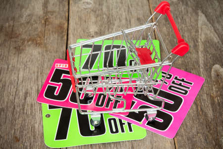 Shopping cart and sale tags on the wood background