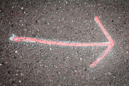 Hand drawn red  arrow on dark asphalt 