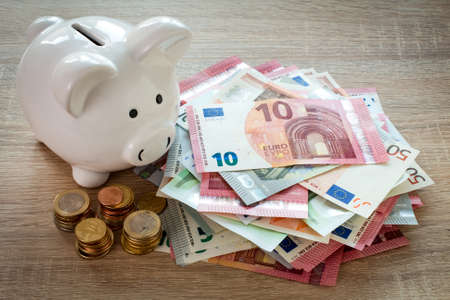 Piggy bank and Euro currency on the wooden tableの写真素材