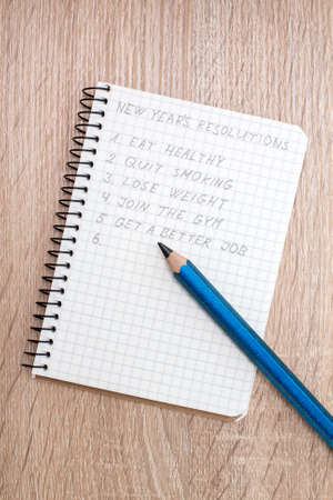 Blue pencil and notepad with New Year's resolutionsの写真素材