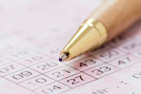 Using a pen to fill out a lottery slip to play the lottoの写真素材