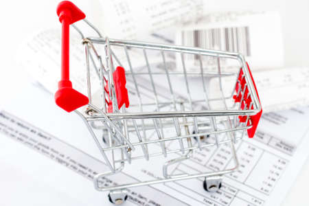 Consumerism concept. Shopping cart with receipts on white backgroundの写真素材