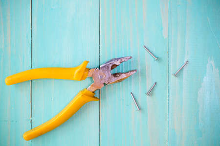 Yellow pliers and few nails on wood backgroundの写真素材