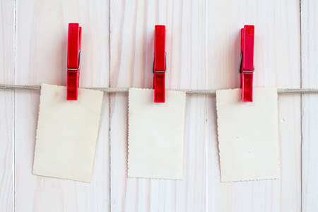 Photo frames hanging on a rope over white wooden backgroundの写真素材