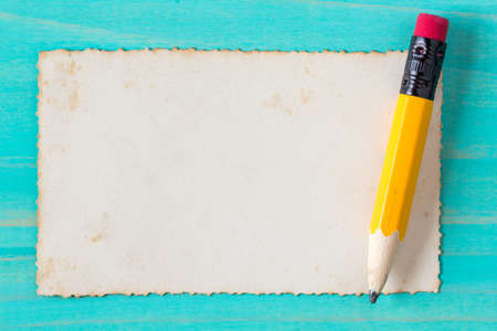 Yellow pencil with old paper on the blue wood surfaceの写真素材