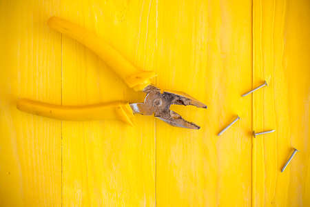 Pliers and few nails on the yellow wood surfaceの写真素材