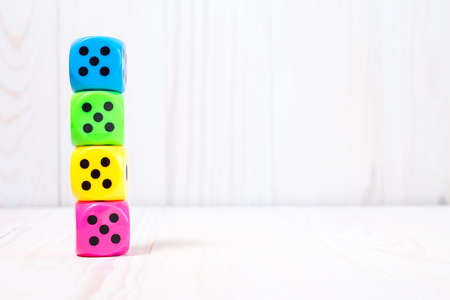 Colorful dice stacked on the white wooden surfaceの写真素材